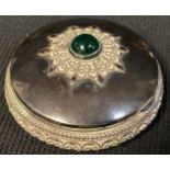 A Middle Eastern silver circular box, applied with filigree, hinged cover centred by a cabochon, the