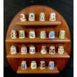 A set of twenty Royal Crown Derby thimbles, assorted patterns, on a wooden wall rack