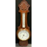 An Edwardian carved oak aneroid barometer thermometer, white scales, shaped and carved frame, 83cm