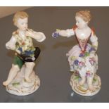 A pair of Meissen figures, of a girl and a boy, both bare foot, seated, she with grapes in her
