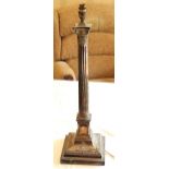 An early 20th century plated Corinthian column candlestick, the base embossed with urns and swags,
