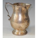 A silver George II style baluster cream jug with double scroll handle, ribbon tied reeded rim,