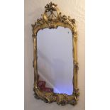 A 20th century giltwood wall mirror, the plate of shaped rectangular form, the frame carved and