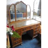 A mid 20th century walnut dressing table, triptych mirror, the base with nine drawers, leafy