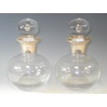 A pair of silver mounted globular clear glass decanters, the stoppers with air bubble inclusion,