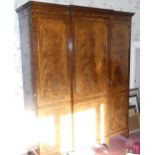 A 20th century mahogany breakfront wardrobe, dentil cornice, three panelled doors, splayed feet,