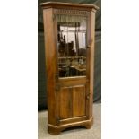 A 20th century Nigel/Rupert Griffiths style oak corner display cabinet, outswept cornice above a