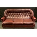 A Pendragon faux leather three seater sofa, ox blood, button back, scroll arm, 94cm high, 185cm