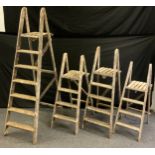 A set of 20th century pine seven tread step ladders; another set of five tread step ladders;