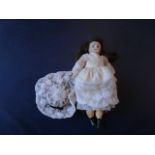 A tiny 6 inch doll with porcelain hand painted face and cloth body. marked ' 5/0' on the back of the