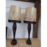 A pair of African carved lamps with vintage parchment shades decorated with real flowers 92cm tall