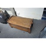 A reproduction oak blanket box with hinged lid above carved panel front, approx 98cm x 47cm x 49cm