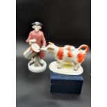 Staffordshire cow creamer figure and a porcelain figurine of a drummer