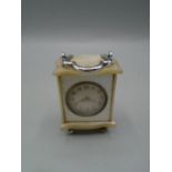 An unusual miniature clock 4cm high in possible mother of pearl case with s/s handle and bun feet