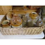 Stoneware jugs, demi-john bottles in a large basket