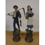 A pair of French figures of lady and gent farmers ladies arm is broken but present, on wooden base