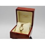 A boxed Rotary ladies watch with baton numerals and yellow metal strap.