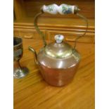 A hammered copper kettle with porcelain handle and lid knob