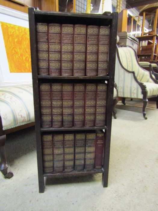 Vintage oak bookcase containing 17 books from the Charles Dickens Library and one other book.