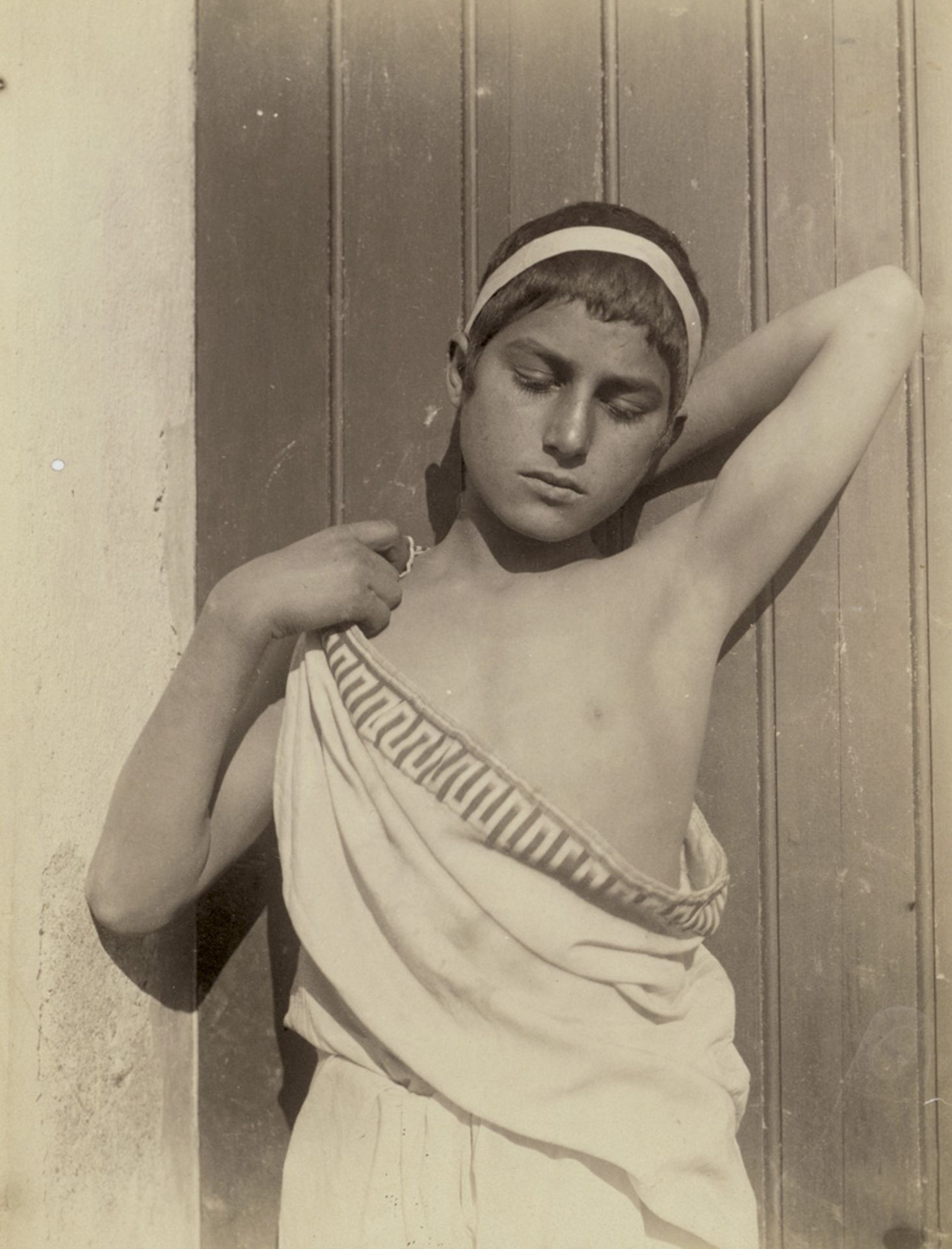 Gloeden, Wilhelm von: Young boy in toga with headband