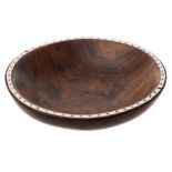 A Soloman Islands hardwood bowl: the rim inlaid with pearl shell, on a circular foot, 23cm wide.