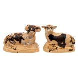 A pair of buff coloured pottery figures of a recumbent ram and ewe,