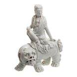 A Chinese Dehua blanc de chine figure group: of a Bodhisattva seated on the back of a Buddhist lion