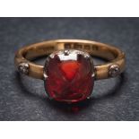 A red spinel and diamond mounted three-stone ring: the rectangular red spinel within a silver