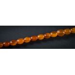 An amber bead single -string necklace: with twenty nine graduated oblong beads,