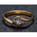 A diamond three-stone cross-over ring: the shank stamped '18ct PLAT', ring size M.
