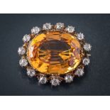 A topaz and diamond oval brooch: the oval topaz approximately 20mm long x 16mm wide x 8.