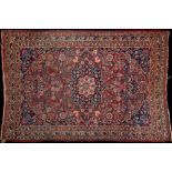 A Meshed rug:, the shaded wine cartouche field with a central indigo flowerhead pole medallion,