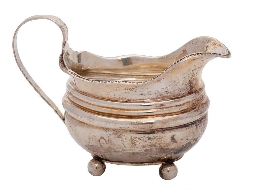A late Georgian silver cream jug, all marks worn: crested,