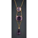 An amethyst mounted three-stone lavalier: suspending a pear-shaped amethyst drop,