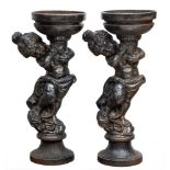 A pair of cast iron planters in the form of putti holding aloft a circular bowl: in the Rococo