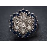 A sapphire and diamond circular cluster ring: set with round brilliant-cut diamonds within a border