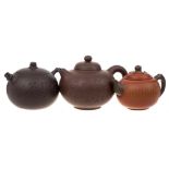 Three Chinese Yixing stoneware teapots: of various hues and of globular form with domed covers,