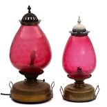 A brass oil fired storm lantern: the circular brass reservoir with large ruby glass shade,