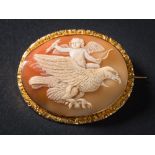 An oval shell cameo mounted brooch: depicting Cupid riding an eagle in flight,