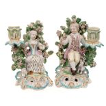 A pair of Derby figural candlesticks: in the form of a seated boy and girl,