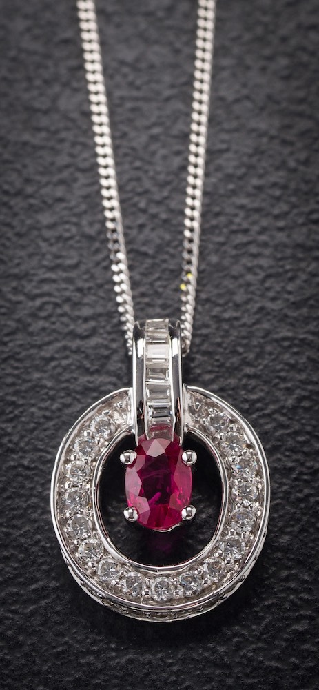 An 18ct white gold, ruby and diamond mounted pendant: with central oval ruby approximately 6.