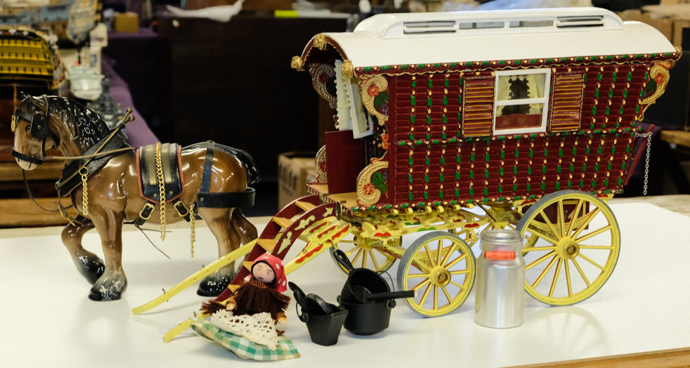 A scale model of a bow top gypsy wagon: white and red with yellow chassis,