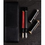 Two Pelikan M400 Souveran fountain pens: one in red, the other in grey, in a leather case.