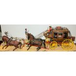 A scale model of a Wells Fargo stagecoach with horses on a diorama base.