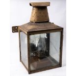 A large station wall lantern: of square form with oval chimney and circular reflector to interior,