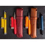Two Viscoti Rembrandt rollerball pens: one red the other orange,