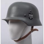 A reproduction German M1935 steel helmet,: grey with insignia and brown leather liner.