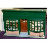 A 20th Century doll's tea shop with green double bay window front, interior figures,