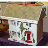 A mid-20th Century tinplate fronted doll's house: the pitched roof over sliding front enclosing