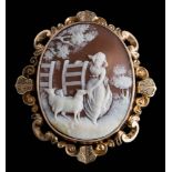 A late 19th century gold and shell cameo brooch: depicting a shepherdess with sheep in a gateway